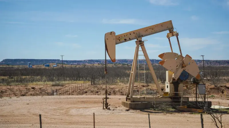 Oil pumpjack in a desert landscape under a blue sky: petroleum experts and advisers