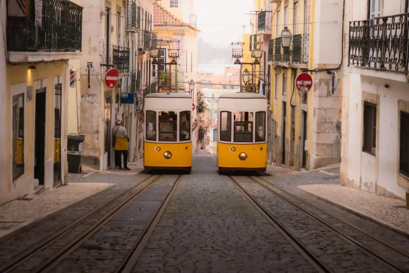 Yellow funicular trams on a steep cobbled street in Lisbon, Portugal: lawyers and advisers in Portugal