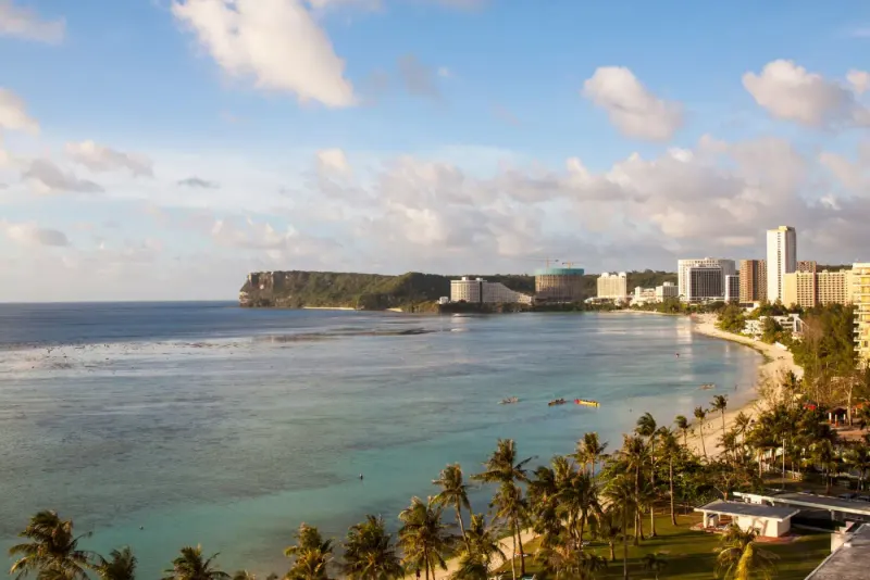 Aerial view of a palm-lined beach and hotel strip on the coast of Guam: lawyers and advisers in Guam
