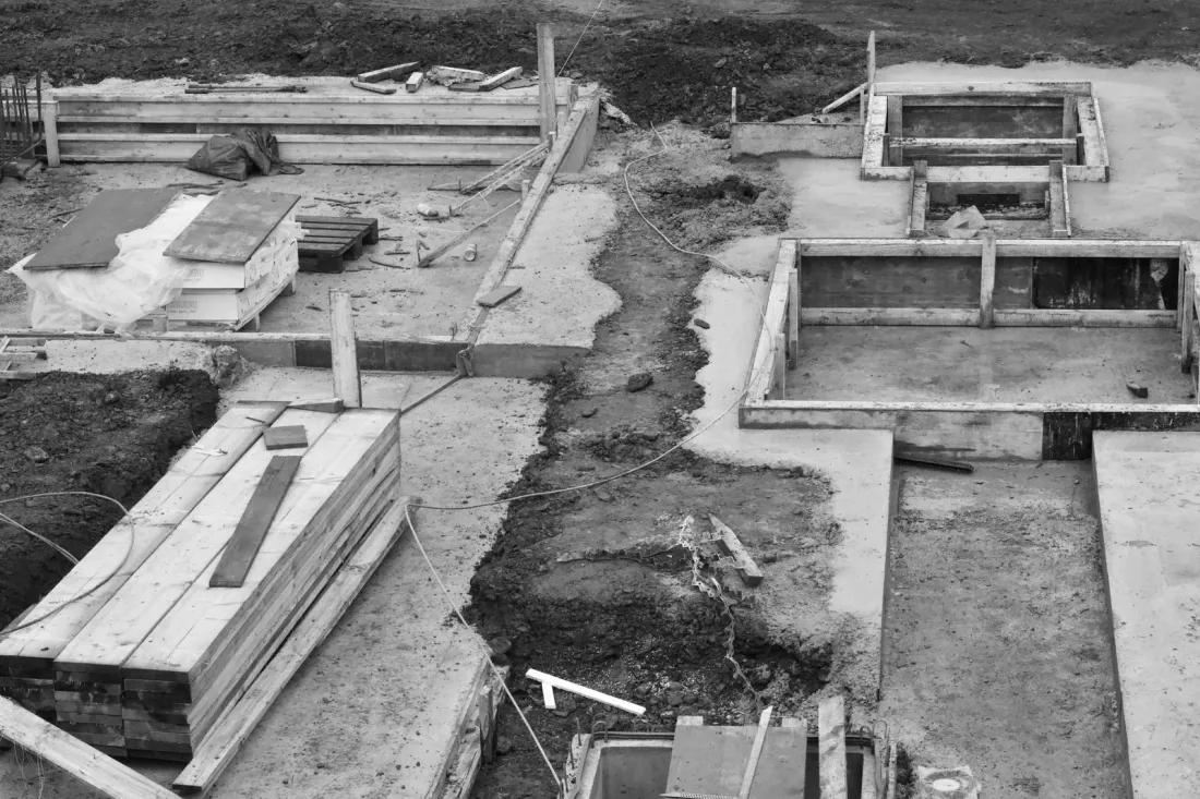 Concrete foundations and stacked timber on a building site, illustrating the construction adjudication process for payment and variation disputes