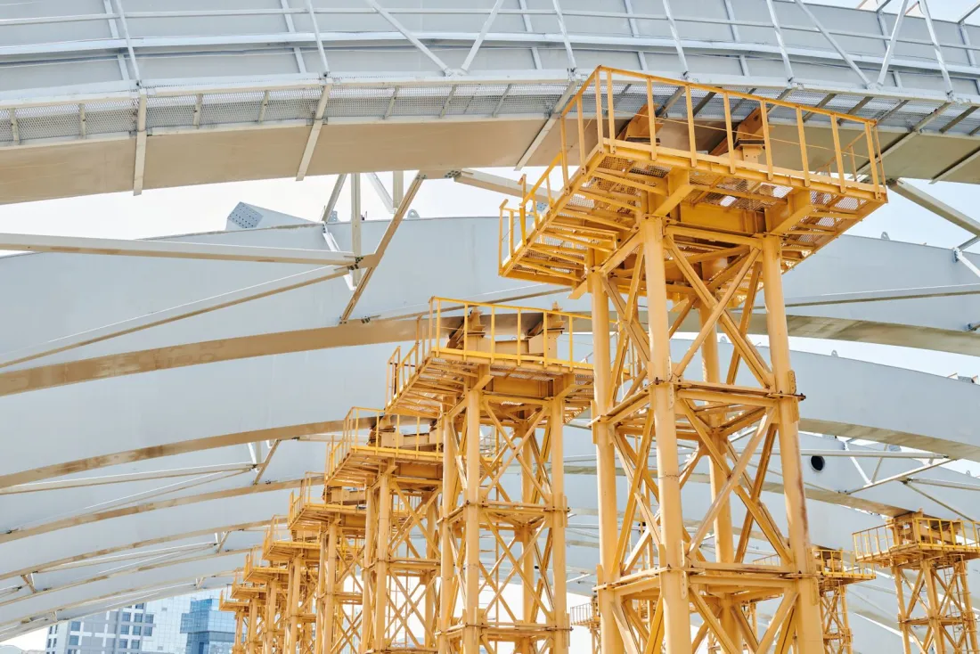 Yellow temporary supports beneath steel roof arches on a large project, illustrating cross-border construction adjudication in the UK and Ireland