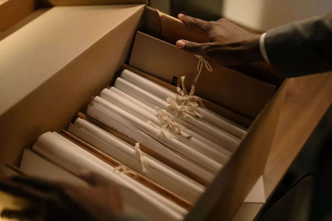 Hands sorting tied document files in an archive box during an internal investigation before an SFO self-report decision