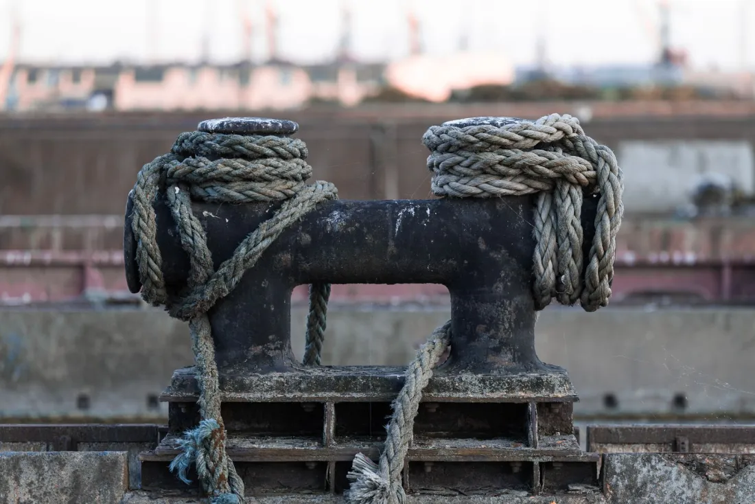 Mooring ropes wound around a bollard on a quay, illustrating ship arrest and a vessel held in port by court order