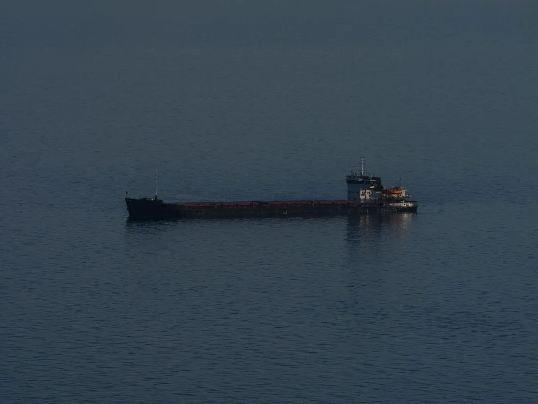 A lone cargo ship at anchor on calm water, illustrating judicial sale after a ship arrest when no security is posted