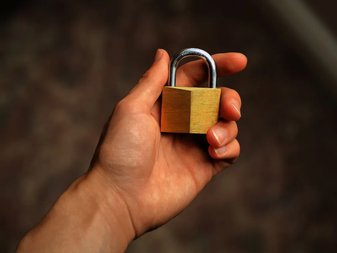Hand holding a brass padlock, representing data breach fines in the UK and EU for late notification