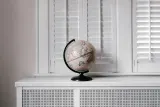 Desk globe by white shutters, illustrating how to choose a wealth manager for a family with assets in several countries