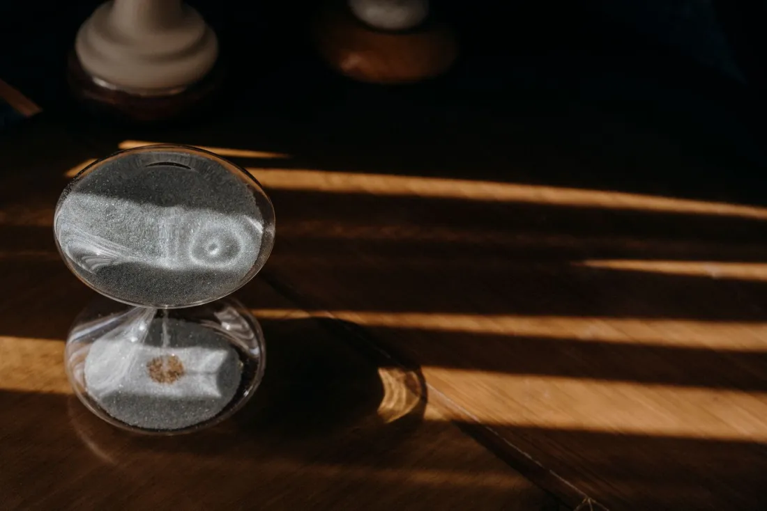 Hourglass on a wooden desk in sunlight, a reminder that ongoing wealth manager fees compound over time