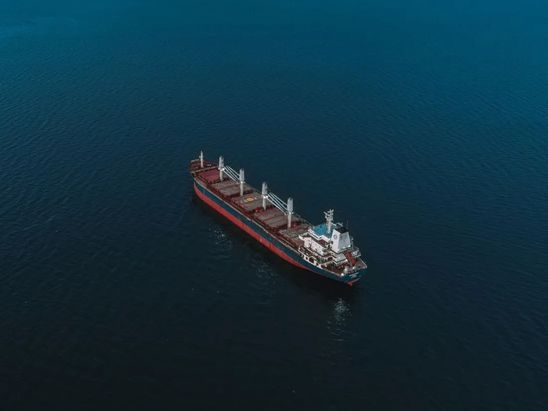 Bulk carrier at sea seen from above, illustrating the time charter vs voyage charter choice for cargo owners and traders