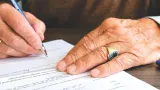 Hands signing a will at a desk, illustrating how to make an international will