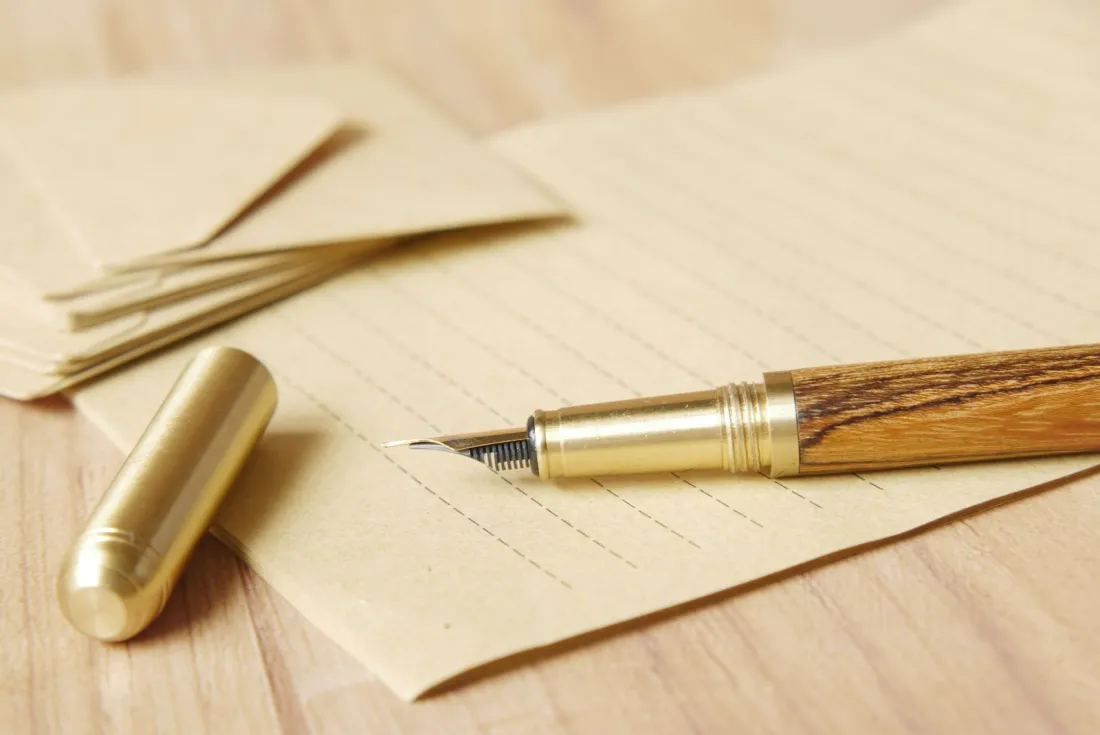 Fountain pen resting on writing paper beside envelopes, representing the signing formalities for wills in more than one country