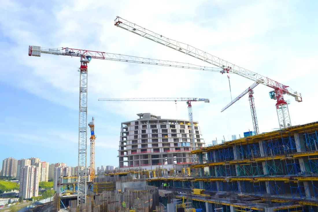 Tower cranes over a high-rise building under construction, illustrating how to choose a construction lawyer