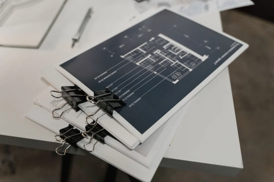 Clipped sets of construction drawings on a table, the contract documents to review when deciding how to choose a construction lawyer