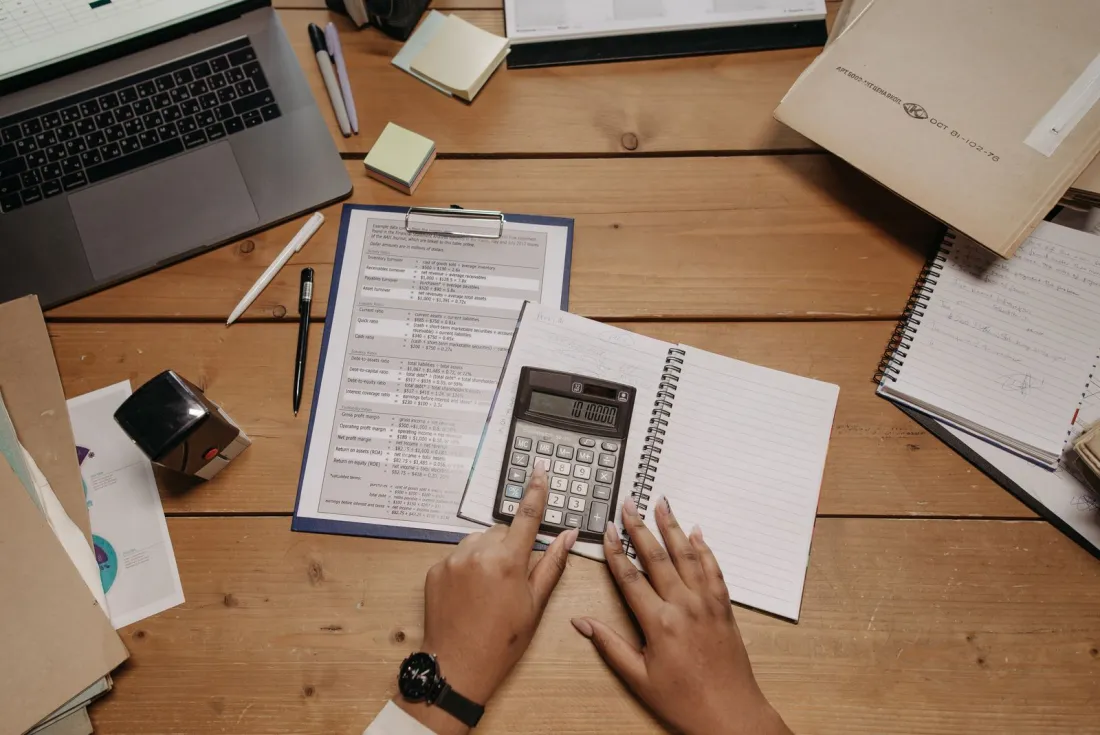 Hands using a calculator over financial papers, illustrating how a child maintenance top up order sits above the CMS formula