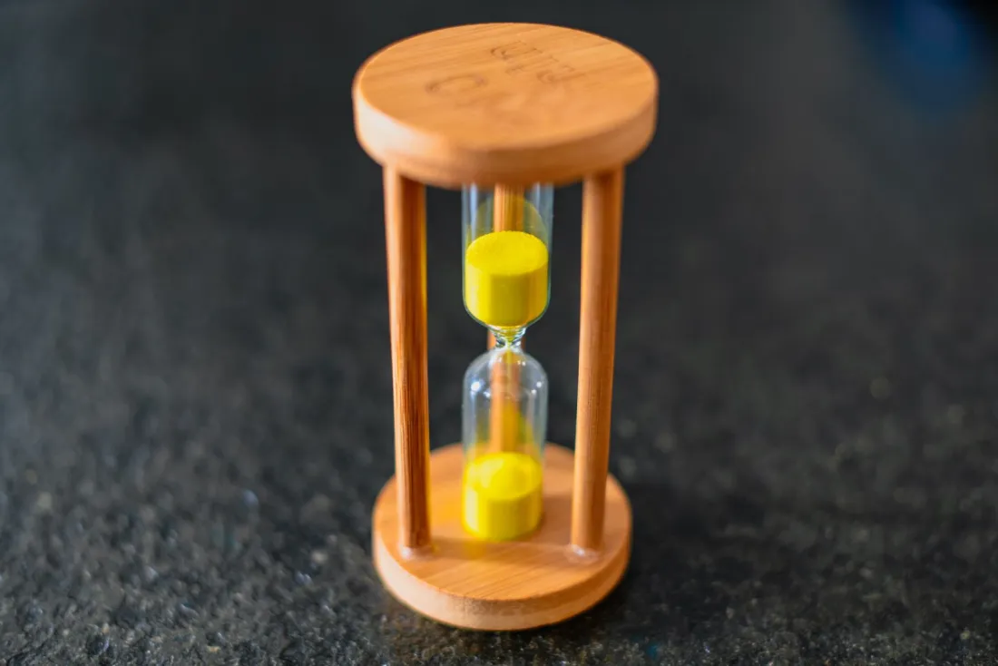 Wooden hourglass with yellow sand, representing timing in claims made vs occurrence policies and notifying circumstances