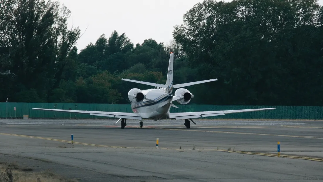 Private jet taxiing on a runway lined with trees, representing delivery and aircraft escrow closing when buying a private jet