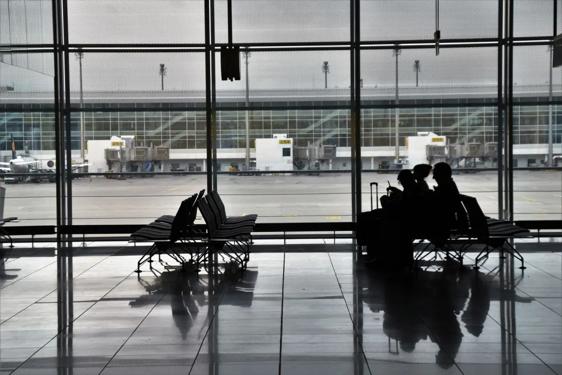 Travellers waiting with luggage in an airport departure lounge, illustrating package deals for surgery abroad