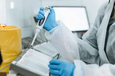 Gloved hand using a micropipette over a sample plate in a laboratory, illustrating the COINS Act biotech investment rules