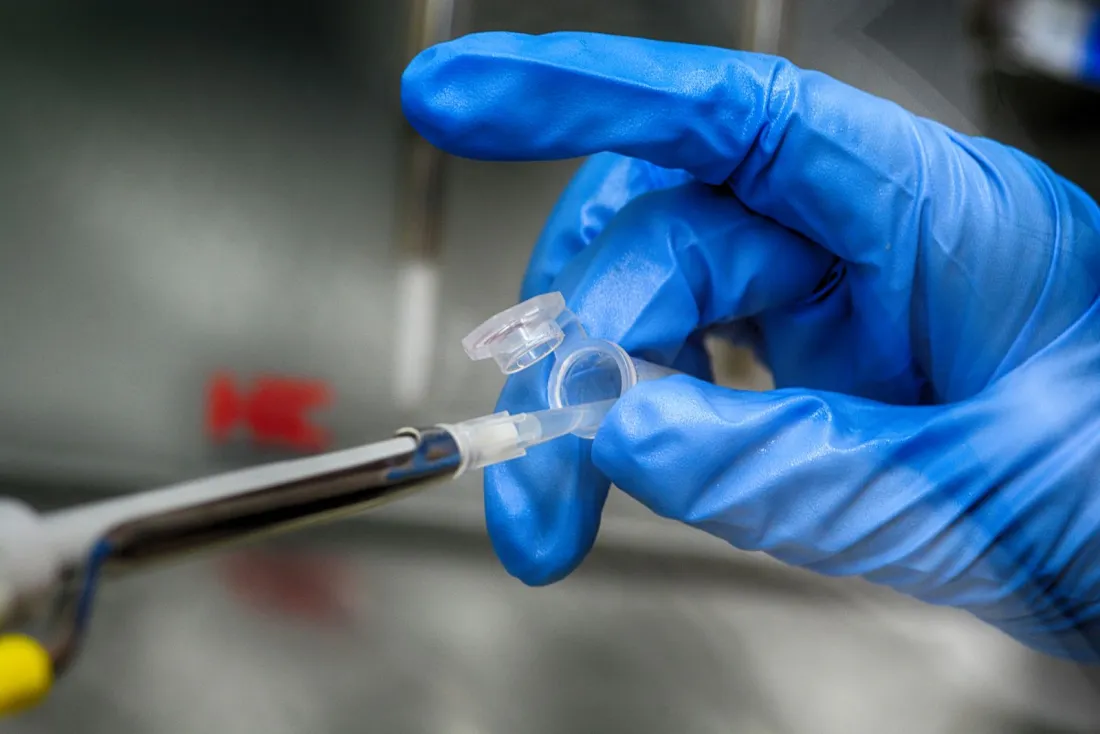 Gloved hand holding a sample tube in a laboratory, illustrating China biotech licensing deals under the outbound investment rules