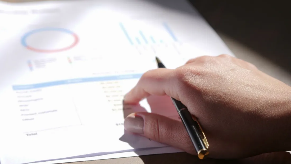 Hand with a pen reviewing a financial report, showing how family office cost is measured against assets