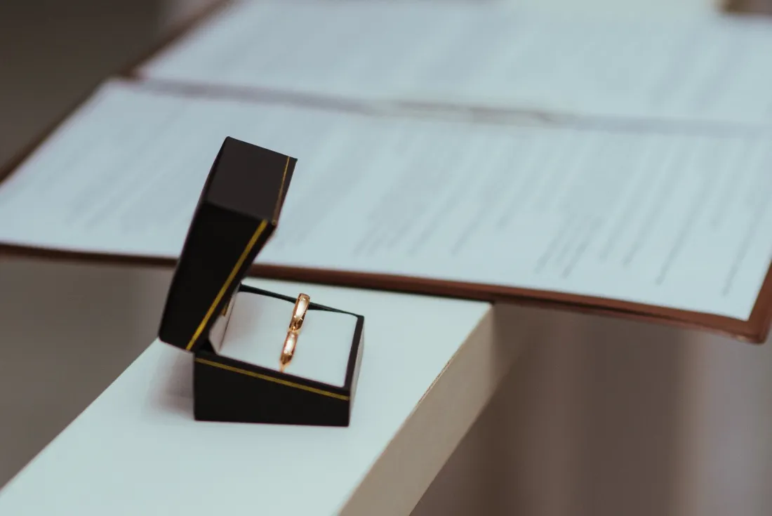 Wedding rings in an open box beside a signed agreement, illustrating the choice between a prenup vs postnup