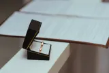 Wedding rings in an open box beside a signed agreement, illustrating the choice between a prenup vs postnup