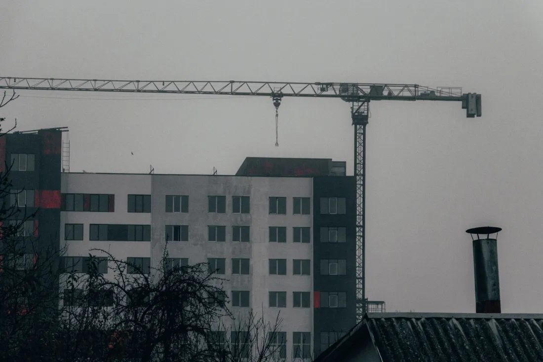Tower crane over a half-finished apartment block on an overcast day, illustrating what happens if your builder goes bust