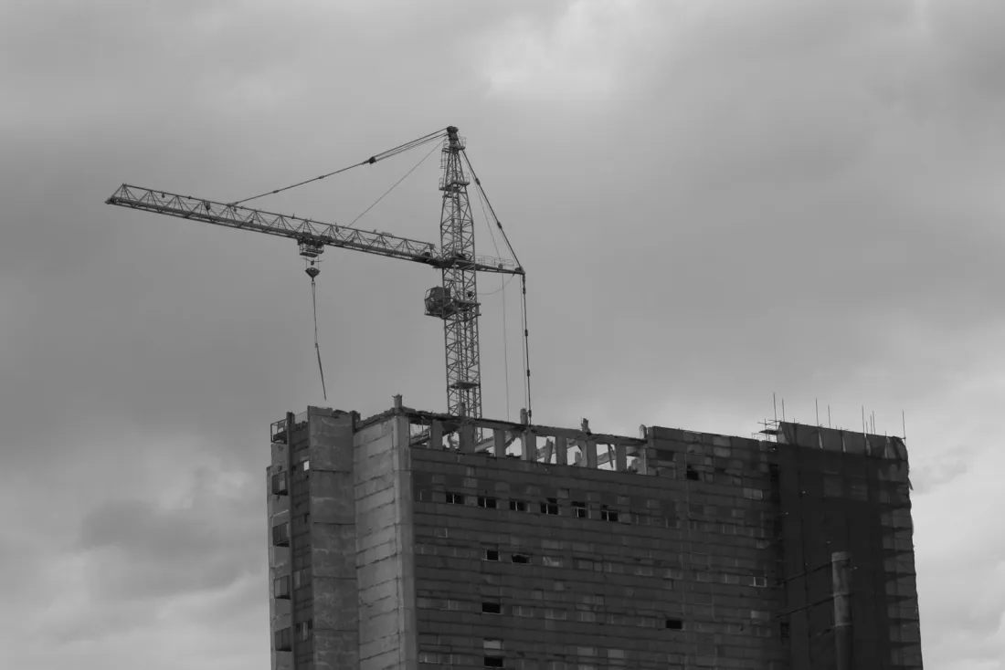 Unfinished concrete building with an idle tower crane, illustrating what happens if your builder goes bust mid-project