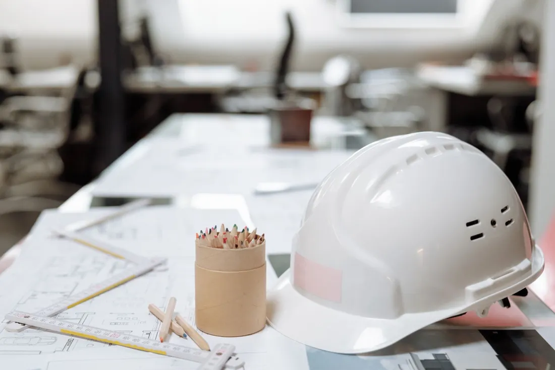 Hard hat resting on construction drawings in a project office, representing performance bond claims after contractor insolvency
