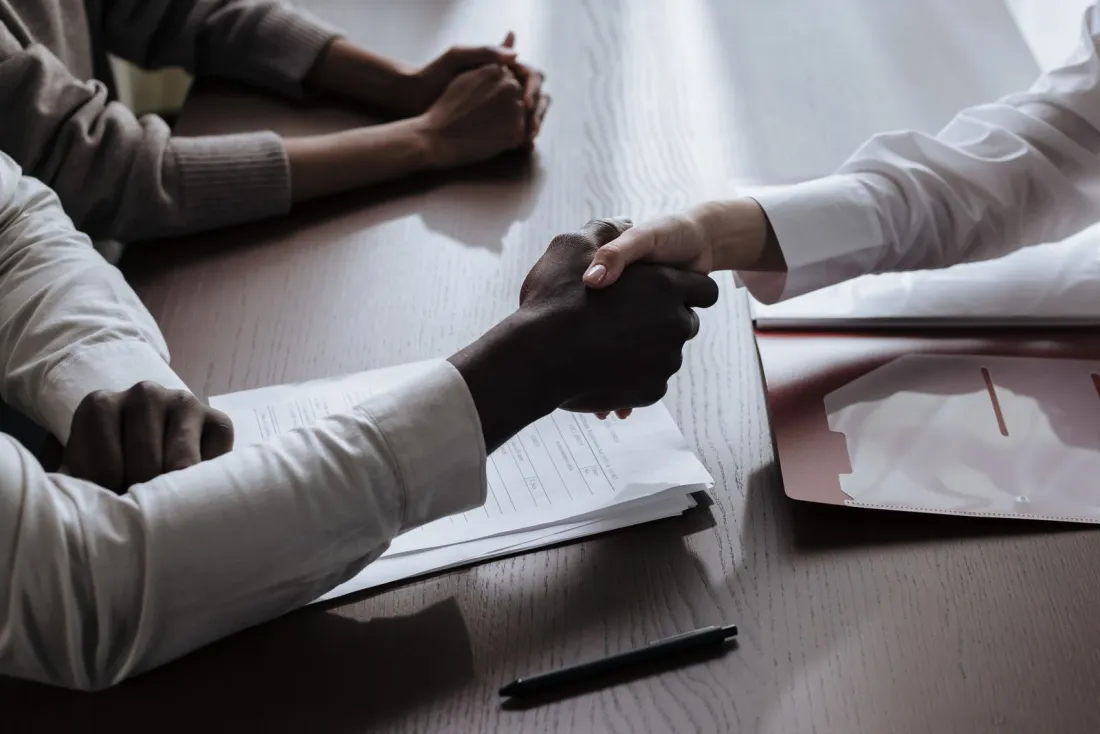 Handshake over signed documents, representing an accountant engagement letter when choosing an international accountant