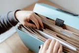 Hands sorting documents in an expanding file folder, preparing to file accounts with Companies House
