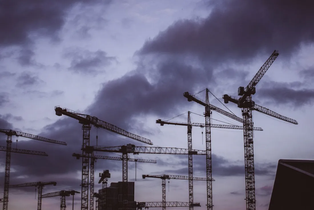 Tower cranes at dusk, illustrating construction as the sector with the most company insolvencies in the year to September 2026