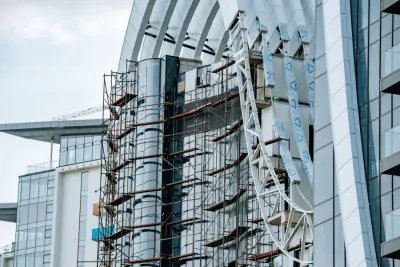 Scaffolding against the curved glass facade of a high-rise under construction, illustrating Building Safety Regulator reforms