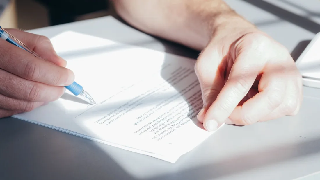 Hand signing a commercial contract with a pen, representing drafting the arbitration seat clause