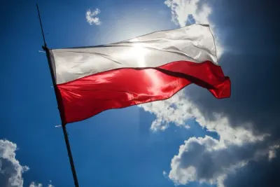 The Polish national flag waving against a bright blue sky, illustrating Japanese capital investment in Poland