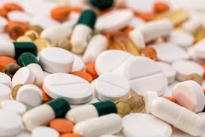 Assorted tablets and capsules scattered together, illustrating pharmaceutical industry returns compliance