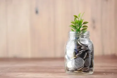 Small plant growing from a glass jar filled with coins, illustrating resilient middle market businesses