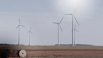 Wind turbines standing across farmland under a hazy sky, highlighting corporate sustainability knowledge gaps