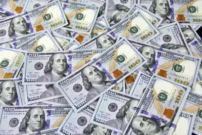 Stack of US hundred dollar bills, representing wages small business owners are raising to close the talent gap