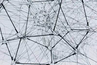 An abstract tangle of interconnected wire lines against a pale sky, symbolising complex workplace networks