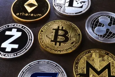 Assorted cryptocurrency coins including Bitcoin and Ethereum arranged on a dark surface, illustrating borrowing to fund crypto