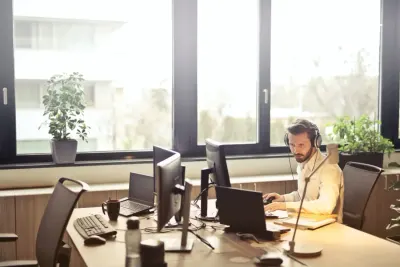 Customer support agent wearing a headset working across several monitors, illustrating customer support trends