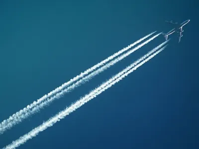 A jet aircraft leaving twin vapour trails across a blue sky, illustrating global consumer confidence hitting a record high