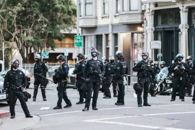 Police officers in riot gear standing in a city street, illustrating threats of violence to companies