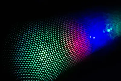 An abstract close-up of a curved grid of glowing green, pink and blue lights, illustrating the pace of digital disruption