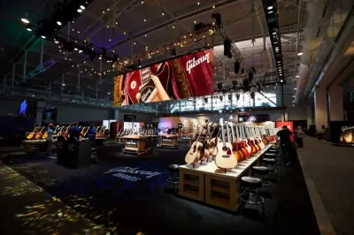 Guitars on display at a music trade show under stage lighting, marking Gibson's return to Japan and China