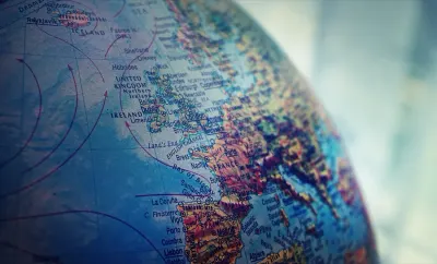 A close-up of a globe showing the UK and Western Europe marked with directional arrows, illustrating the coming global order