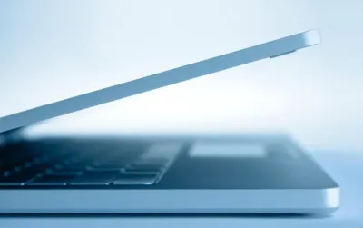 Close-up of a laptop's edge and keyboard in cool blue light, representing data security strategies