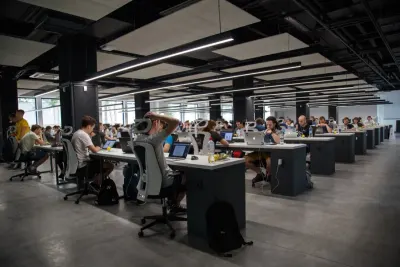 Rows of employees working at desks in a busy open plan office, reflecting demand for office support staff