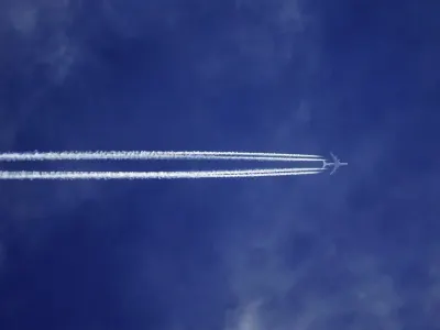 A jet aircraft leaving twin vapour trails across a deep blue sky, illustrating concerns over consumer confidence