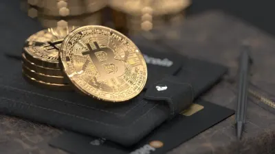 Gold bitcoin coins stacked on a wallet beside a bank card and pen, illustrating trends in digital finance